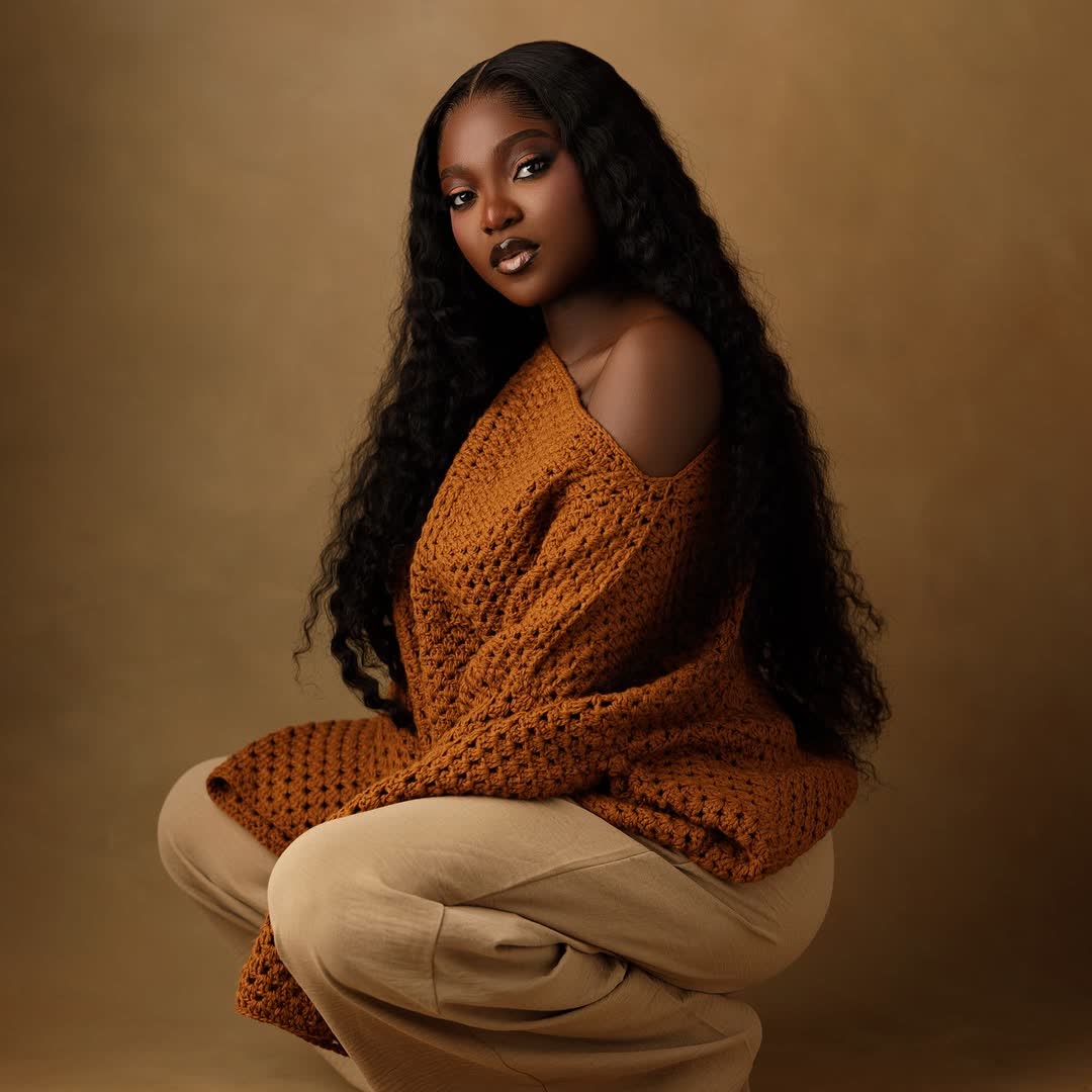 Woman seated in rust sweater, studio portrait