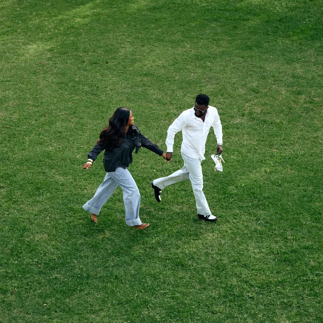 Couple walking hand-in-hand on green lawn