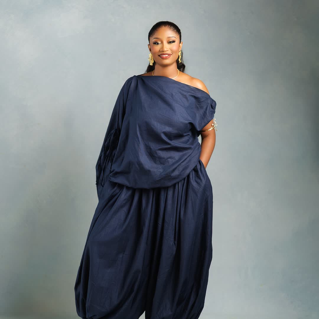 Woman in draped navy blue outfit, studio